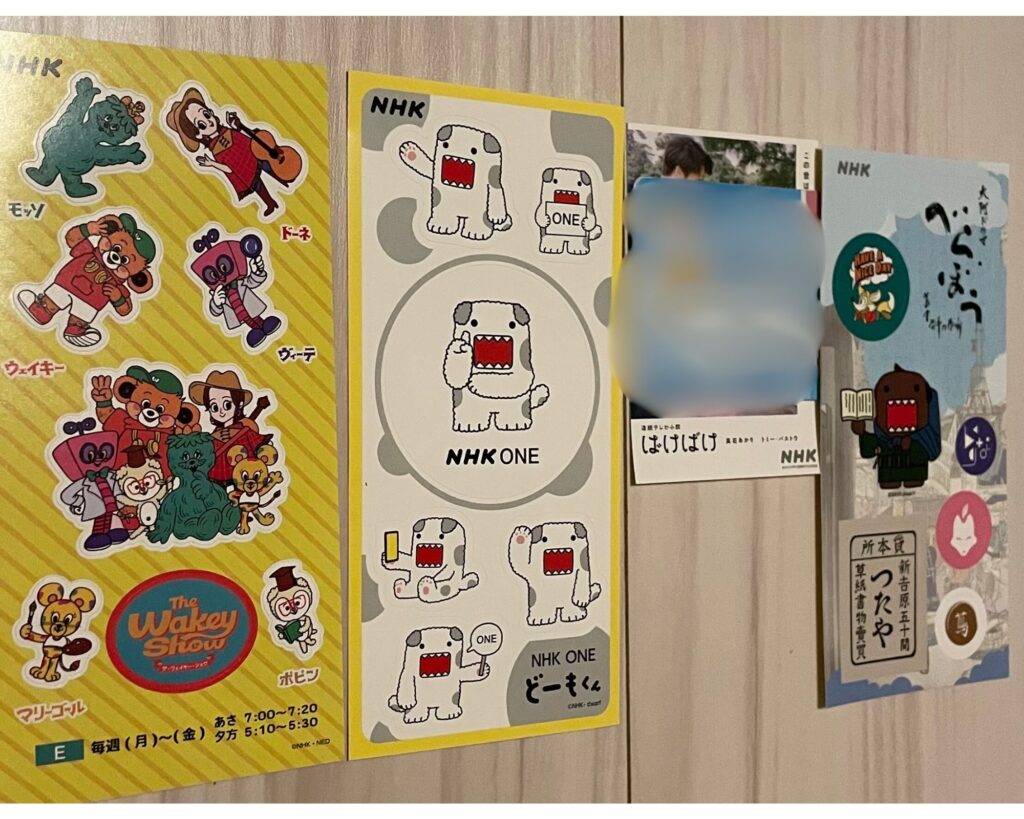 Various NHK character stickers displayed on a wall, featuring brightly colored cartoon characters and logos.